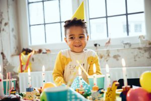 Kind hat Geburtstag und schaut glücklich auf Geburstagskerzen