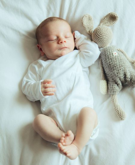 Baby schlafend mit Kuscheltier im Familienbett